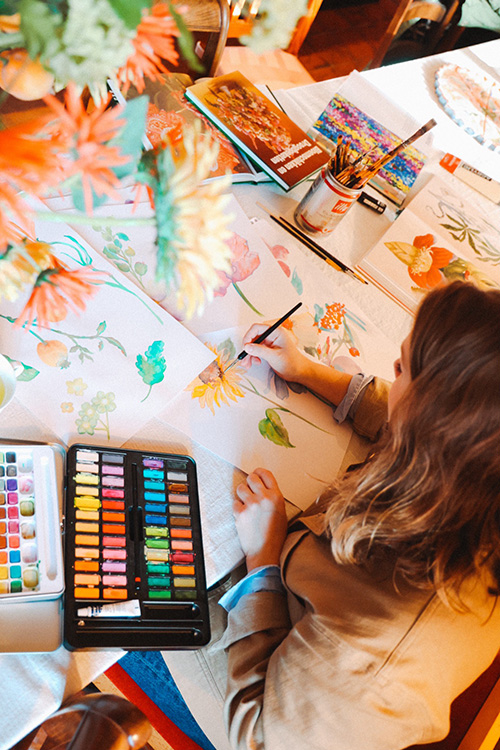 Marylène Madou painting watercolor flowers at table